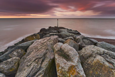 Scenic view of rocks in sea against sky during sunset