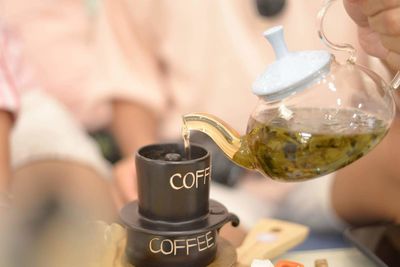 Cropped hand pouring tea in cup