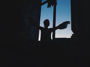 Silhouette woman looking through window