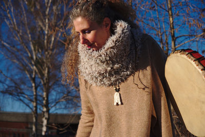 Woman in warm clothes holding drum