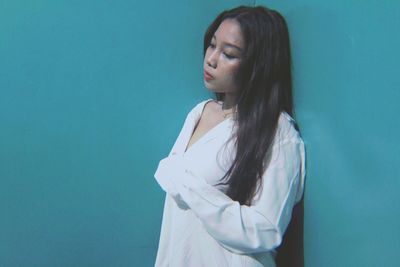 Young woman looking away against blue background