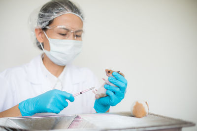 Doctor giving injection to rat against white background