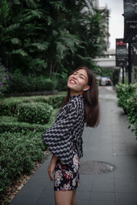 Happy woman standing on footpath