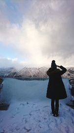 Rear view of woman on snow covered landscape during sunset