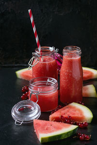Close-up of juice with watermelon and red currants on table against wall