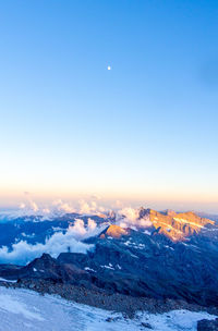 Scenic view of snowcapped mountains against clear sky at sunset