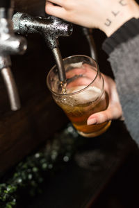 Midsection of man drinking beer in glass