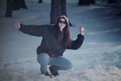 Woman kneeling on snow in forest