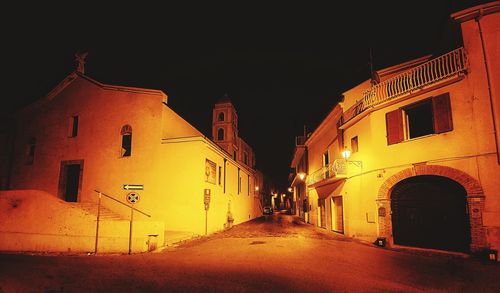 Empty road amidst buildings at night