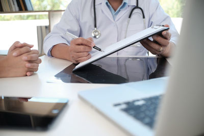 Midsection of man holding smart phone on table