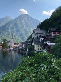 Houses by buildings and mountains against sky