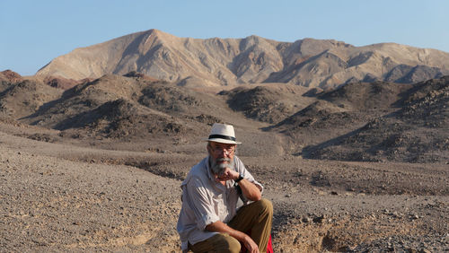Senior man sitting on mountain in the desert 