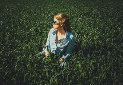 Beautiful woman wearing sunglasses while sitting on grassy field