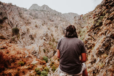 Rear view of man sitting against mountains