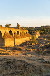 Arch bridge on landscape against sky