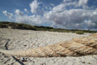 Close-up of rope tied on field against sky