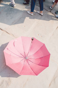 Low section of man standing on pink umbrella