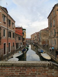 Canal amidst buildings in city against sky