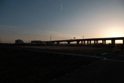 Bridge over road against sky at sunset