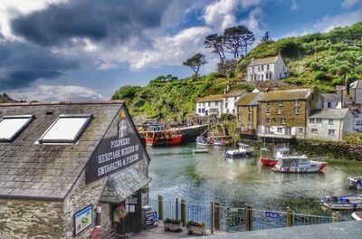 Buildings by canal against cloudy sky