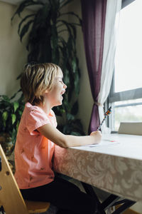 Side view of young woman sitting on bed at home