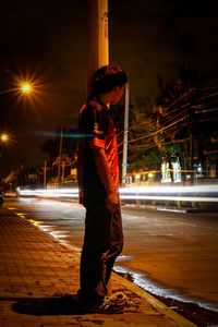 Man standing on road at night