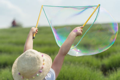 Girl playing with bubbles in field