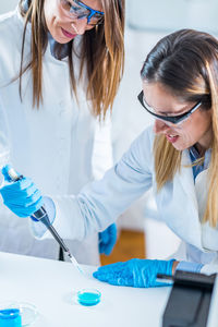 Female scientists examining chemical in laboratory