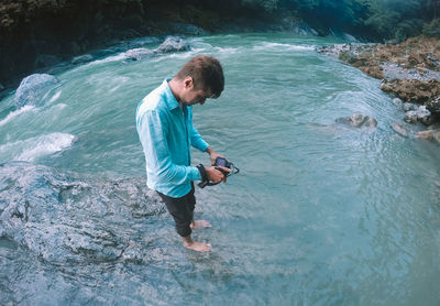 Full length of man photographing while standing in river