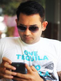 Portrait of young man holding sunglasses