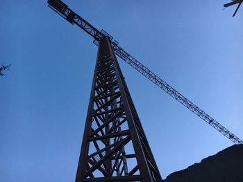 Low angle view of crane against clear blue sky