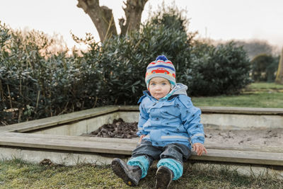 Portrait of cute boy wearing knit hat against trees