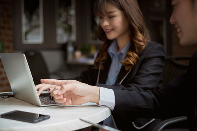 Midsection of woman using phone while sitting on table