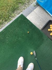 Low section of man standing by ball on golf club on turf