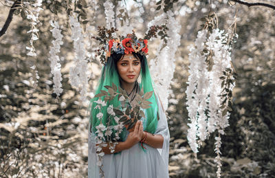 Portrait of woman standing by flower plants