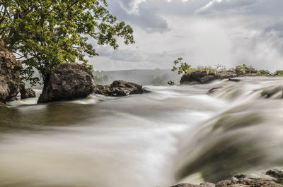 Scenic view of waterfall against sky