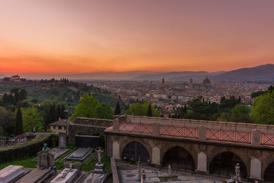 Arch bridge and buildings against sky during sunset