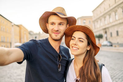 Portrait of smiling young woman wearing hat standing outdoors