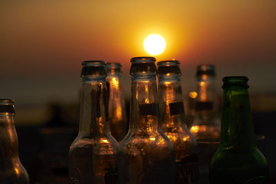 Close-up of beer glass bottle against orange sunset