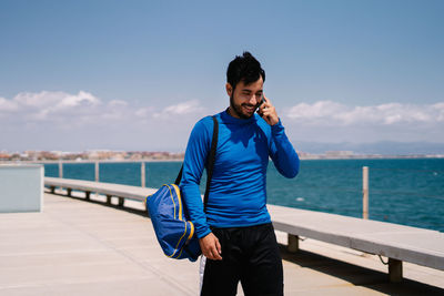 Young man standing by sea against sky