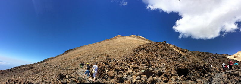 Low angle view of people hiking on mountain against sky