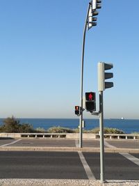 Road by sea against clear blue sky