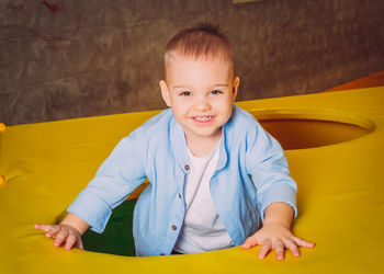 Portrait of cute boy sitting on bed at home