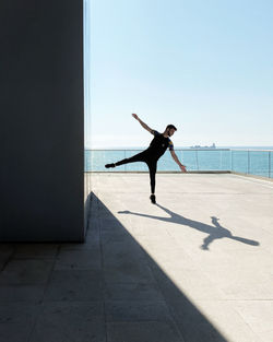 Full length of man with arms raised in sea against sky