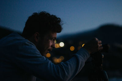 Portrait of young man holding camera at night