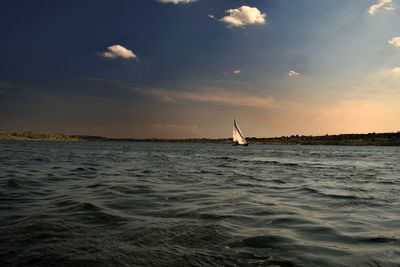 Sailboat sailing on sea against sky during sunset