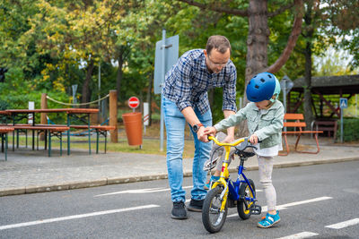 Rear view of boy riding push scooter on road