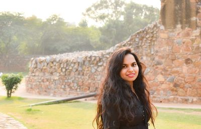 Portrait of smiling young woman against wall