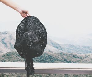 Close-up of woman holding hat against mountain range