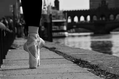 Low section of ballet dancer dancing on pavement in city